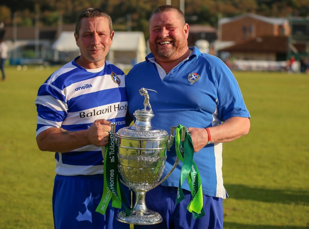 Russwood's Operations Director PJ Mackintosh holding the Camanachd cup with Glen.