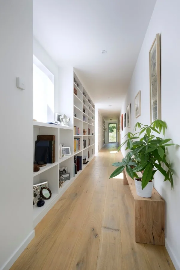 Russwood Unfinished Oak Flooring hand oiled Raw Osmo in a long hallway with plants and inbuilt shelving with a window.