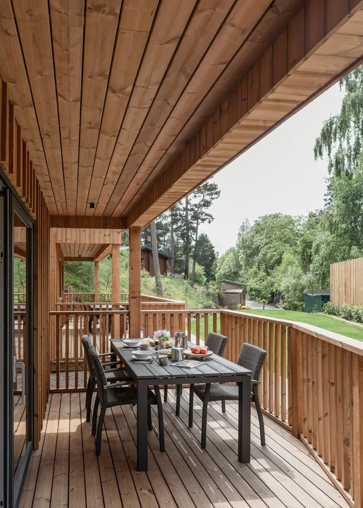 A portrait photo of the Pine Bank Chalets showing the Thermopine decking and a wooden table with chairs and the table set.