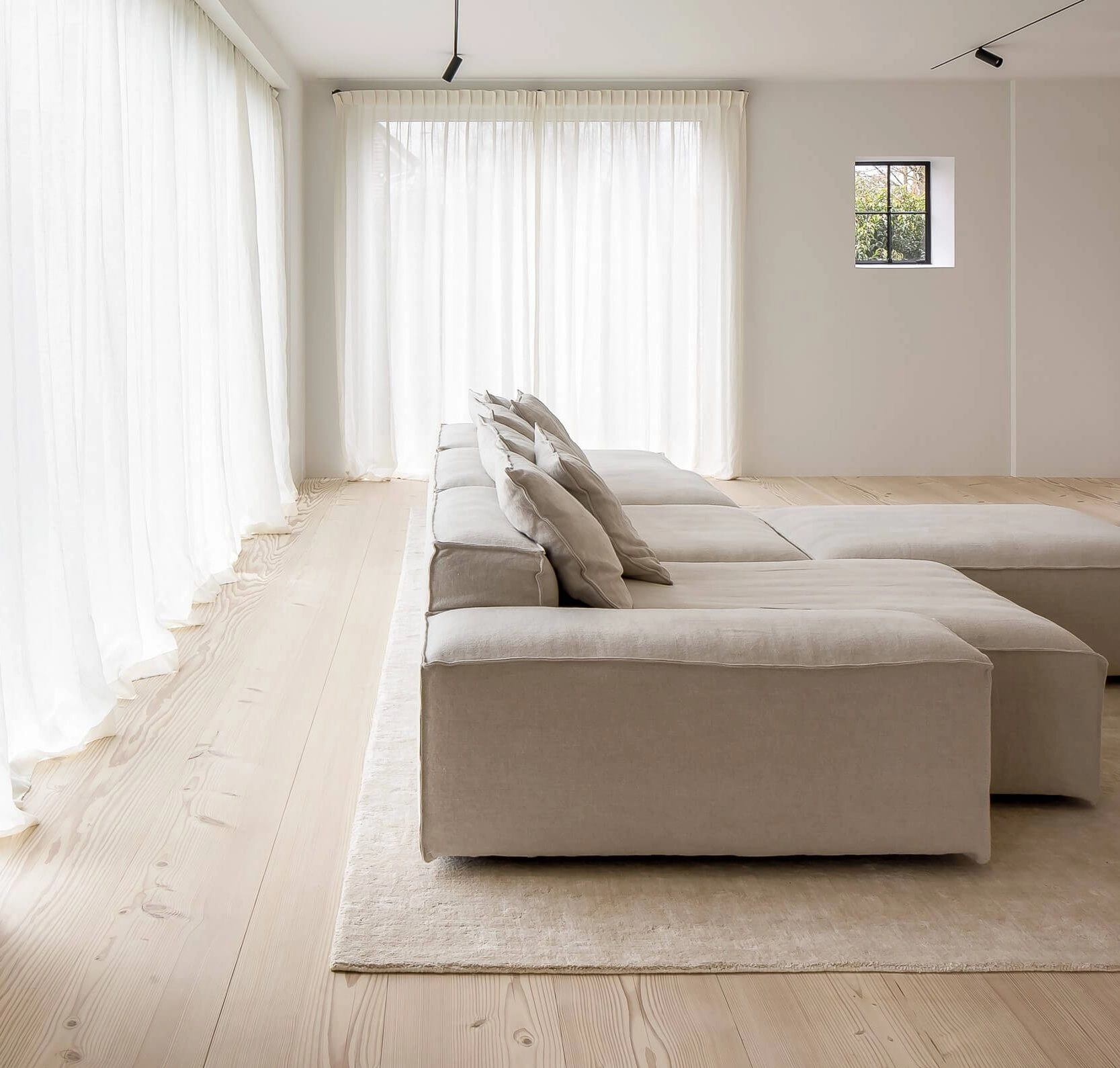 Russwood Douglas Fir Flooring prefinished in Signature White in a minimalist living room with a sofa and a rug with closed curtains.