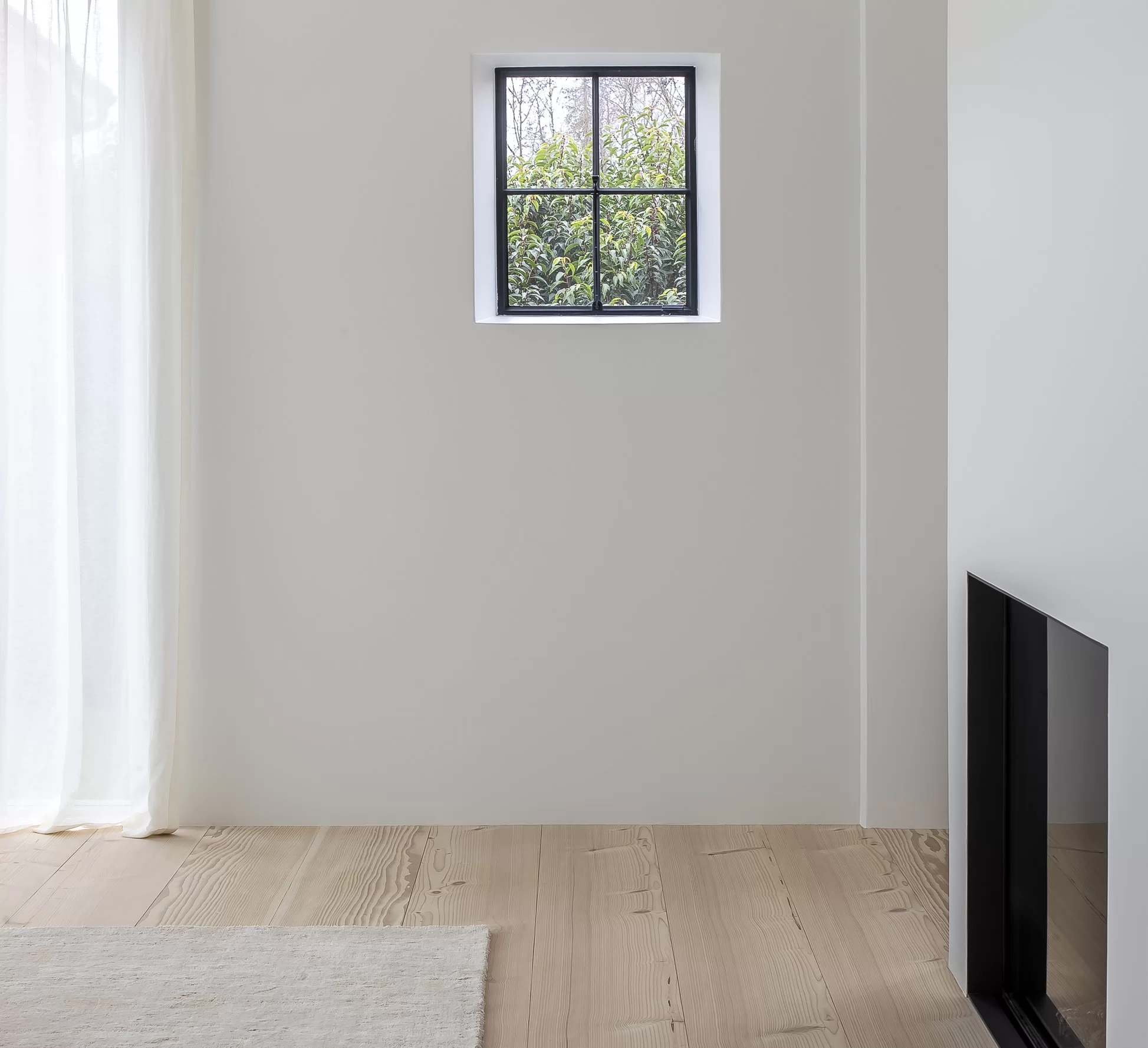 Russwood Douglas Fir Flooring prefinished in Signature White used as interior cladding in a room with a high window and an electric fireplace.