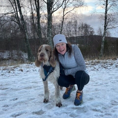 A picture of Claire and her dog, Bruno, in the woods during the winter